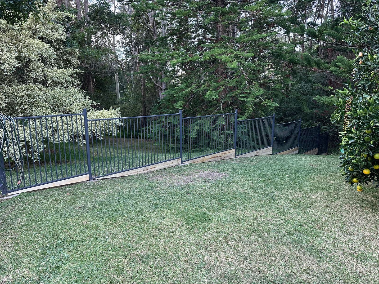 Black tubular steel garden perimeter fence + access gate, sleeper base