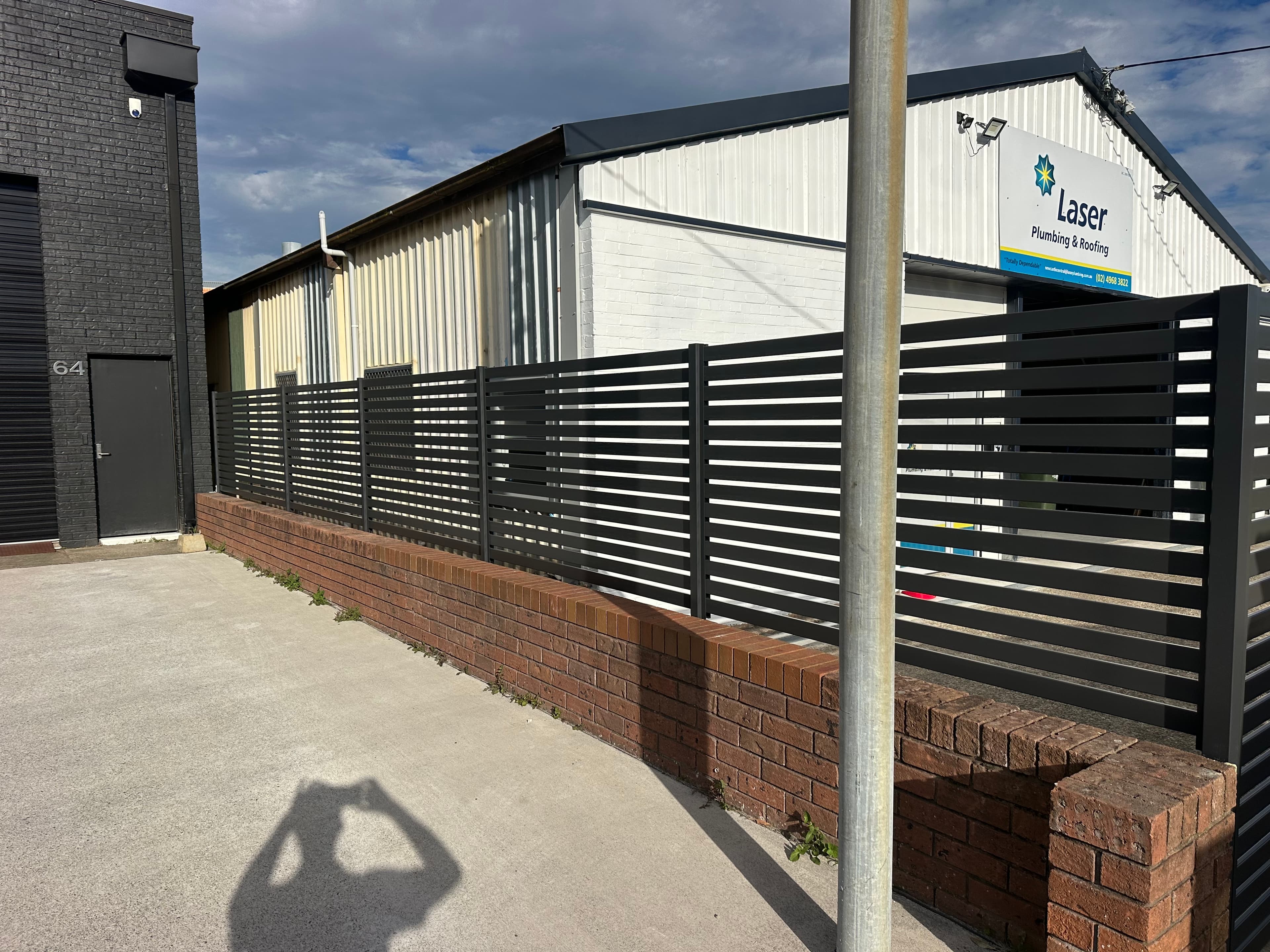 Charcoal aluminium horizontal slat fence — brick base, close detail