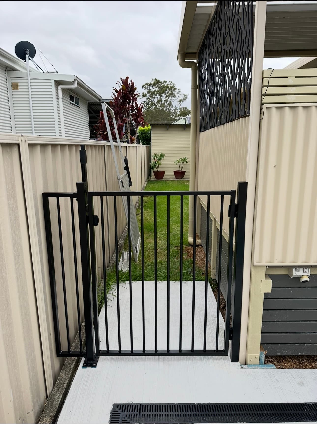 Black flat-top steel pedestrian gate + matching panel — side path access
